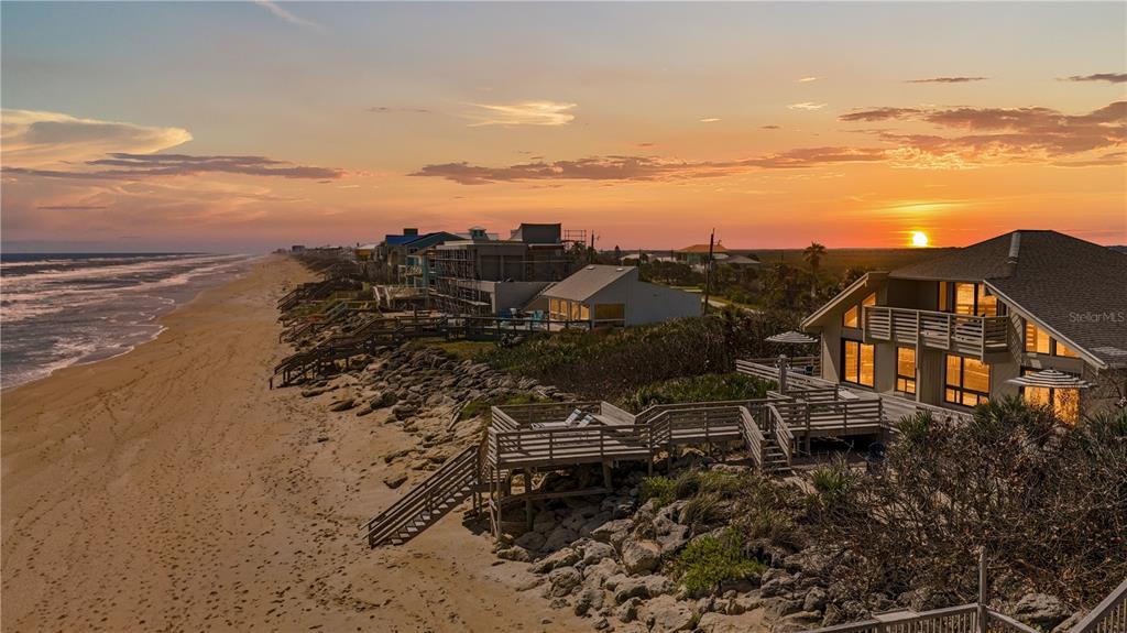 An aerial view of a beach house with a wooden deck overlooking the ocean at sunset — 6007 S ATLANTIC AVENUE, NEW SMYRNA BEACH, FL