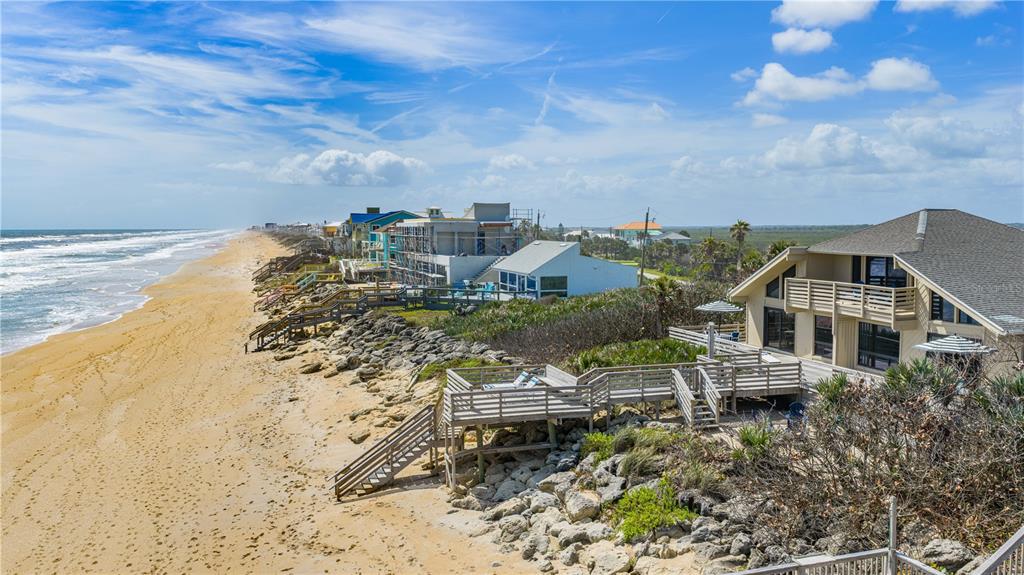 An elevated view of a beach house with a wooden deck overlooking the sandy shore — 6007 S ATLANTIC AVENUE, NEW SMYRNA BEACH, FL