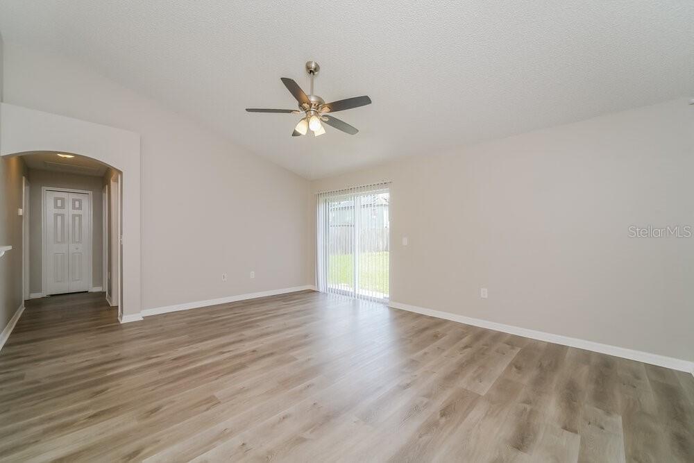 An empty room with light wood-look flooring, a ceiling fan, and sliding glass patio doors — 5537 WILLOW BEND TRAIL, KISSIMMEE, FL