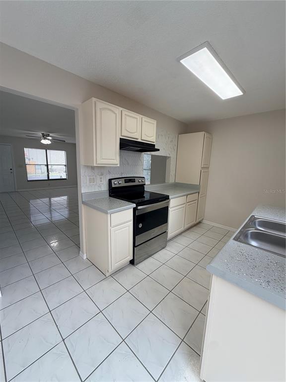 A kitchen features white cabinets, stainless steel appliances, gray countertops, and white tile flooring — 1625 LONG RIDGE COURT UNIT 271, ORLANDO, FL