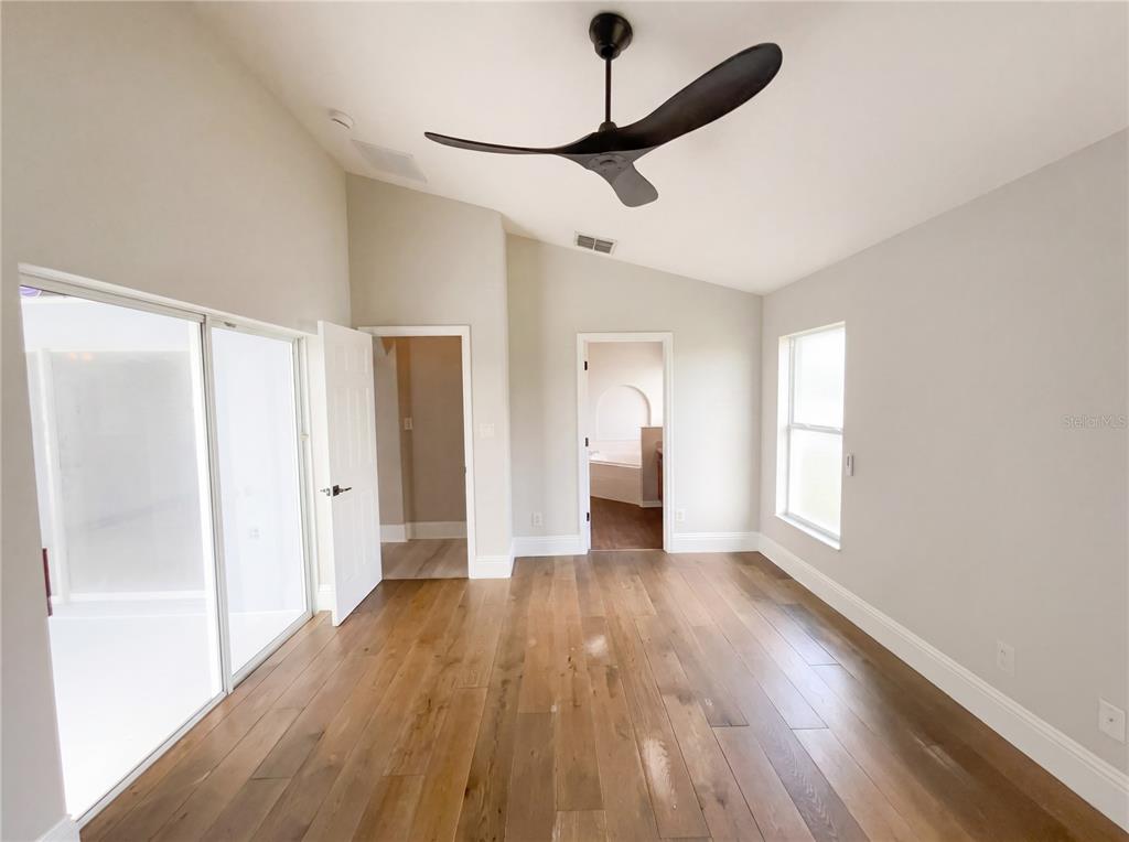 A bedroom with hardwood floors, a vaulted ceiling, a ceiling fan, and two doorways — 3028 SAMOSA HILL CIRCLE, CLERMONT, FL