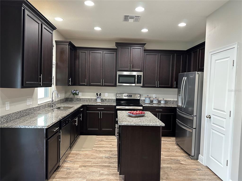 A kitchen features dark wood cabinets, granite countertops, stainless steel appliances, and a central island — 3313 W WALNUT STREET, TAMPA, FL