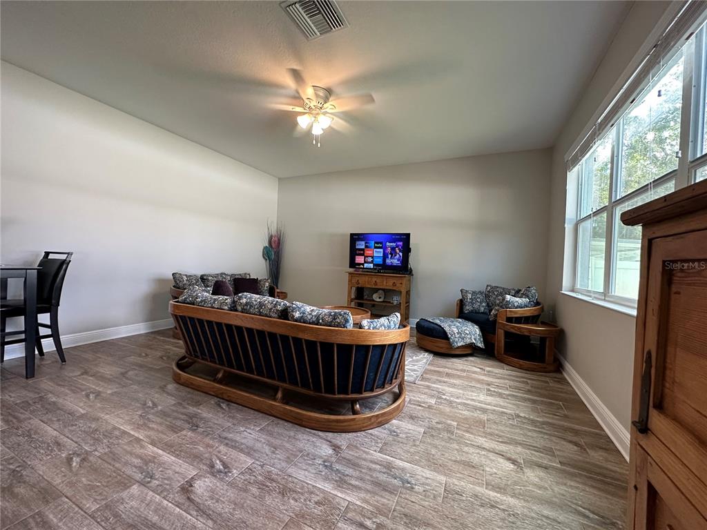 A living room features wood-framed furniture, tile flooring, a ceiling fan, and a television — 3313 W WALNUT STREET, TAMPA, FL