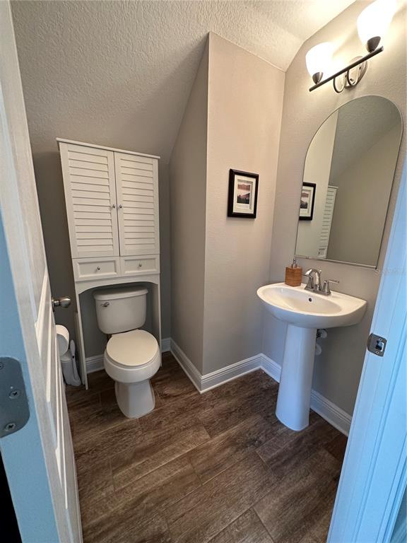 A small bathroom features a pedestal sink, a toilet with overhead storage, and wood-look flooring — 3313 W WALNUT STREET, TAMPA, FL