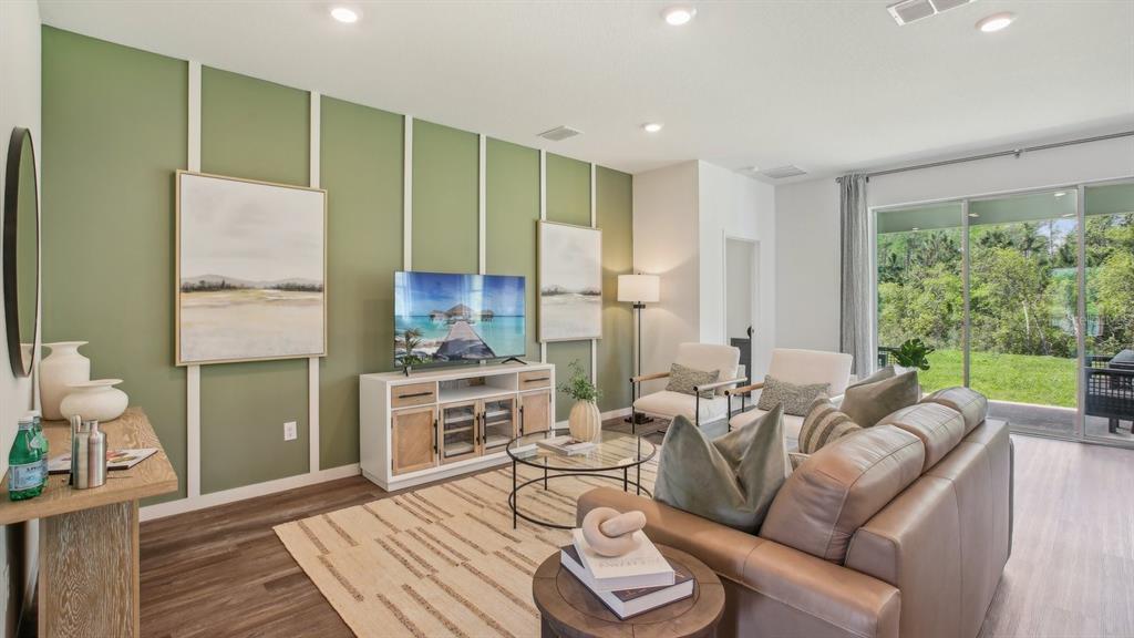 A living room features a green accent wall with white trim, a sofa, and sliding doors — 36237 HILLRIDGE TRAIL, ZEPHYRHILLS, FL
