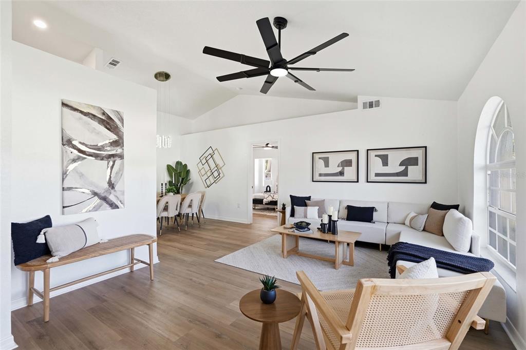 A bright living room features white walls, wood-look flooring, a sectional sofa, and a ceiling fan — 4850 S SALFORD BOULEVARD, NORTH PORT, FL