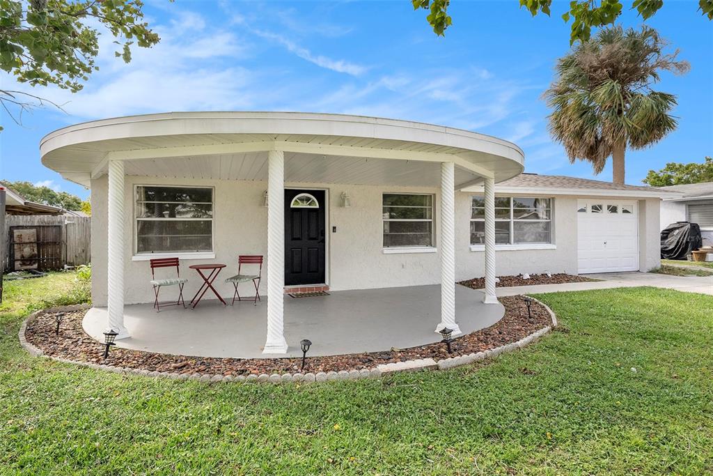 A single-story house features a curved front porch with white columns and a black door — 3510 ALLANDALE DRIVE, HOLIDAY, FL