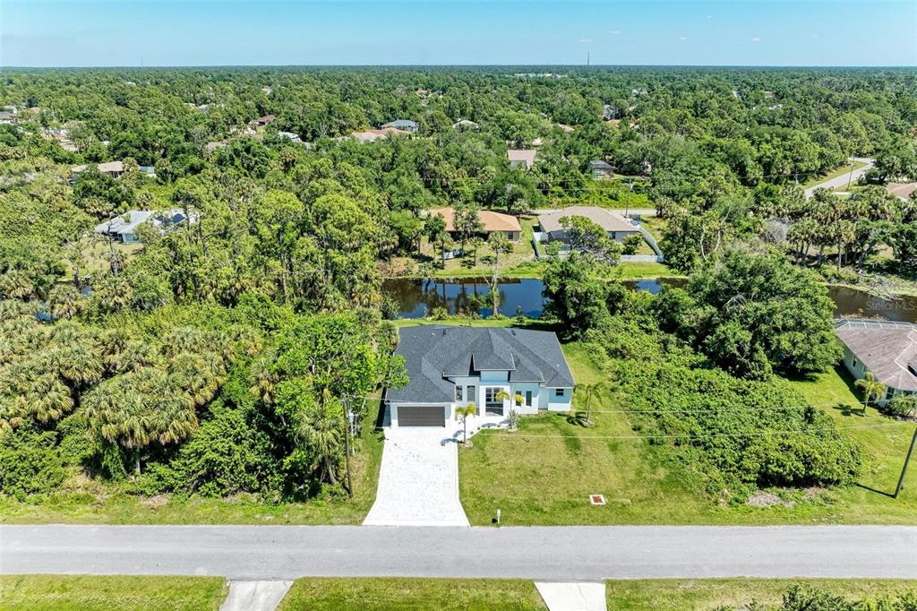An aerial view shows a single-story house with a white driveway and a backyard canal — 3260 ABBOTSFORD STREET, NORTH PORT, FL