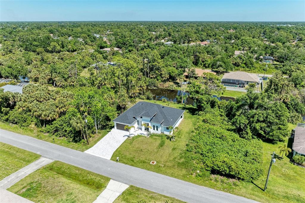 An aerial view of a single-story house with a dark roof and a paved driveway — 3260 ABBOTSFORD STREET, NORTH PORT, FL