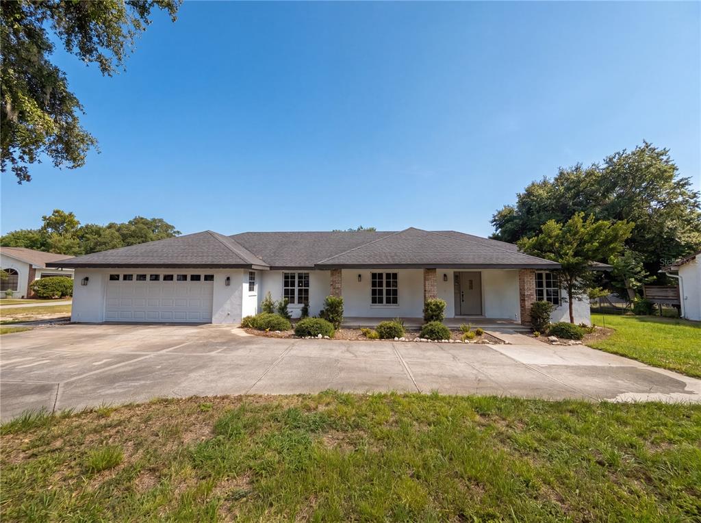 A single-story white house with a two-car garage and a concrete driveway — 11200 ROSEHILL DRIVE, CLERMONT, FL