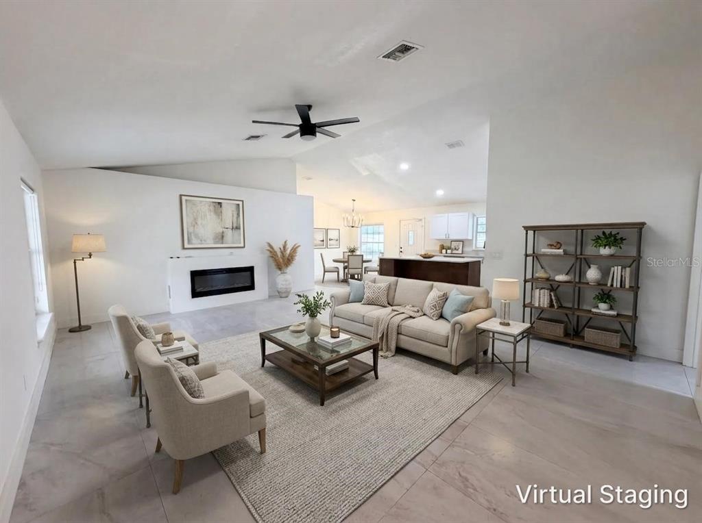 A living room with a fireplace, sofa, armchairs, and a bookshelf on tiled flooring — 11200 ROSEHILL DRIVE, CLERMONT, FL