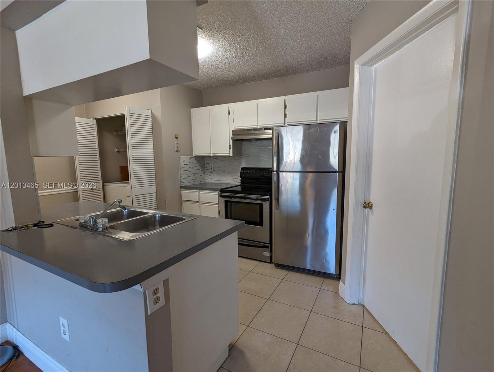 A kitchen features white cabinets, stainless steel appliances, a gray countertop, and tile flooring — 18308 NW 68th Ave # D, Hialeah FL 33015, HIALEAH, FL