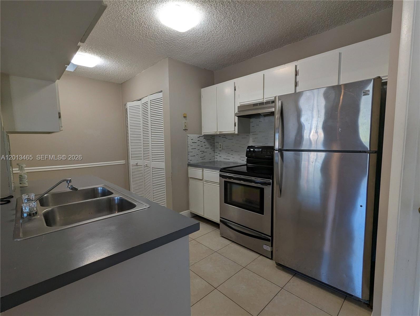 A kitchen features stainless steel appliances, white cabinets, and a double sink with gray countertops — 18308 NW 68th Ave # D, Hialeah FL 33015, HIALEAH, FL