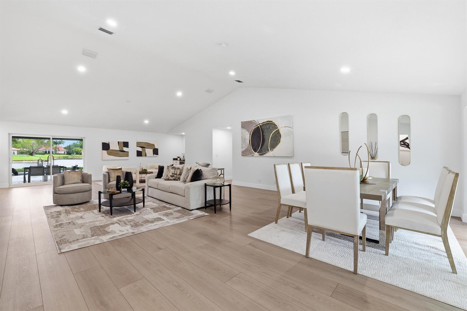 A bright, open-concept living and dining area features light wood floors and a vaulted ceiling — 7411 Dover Lane, Parkland FL 33067, PARKLAND, FL