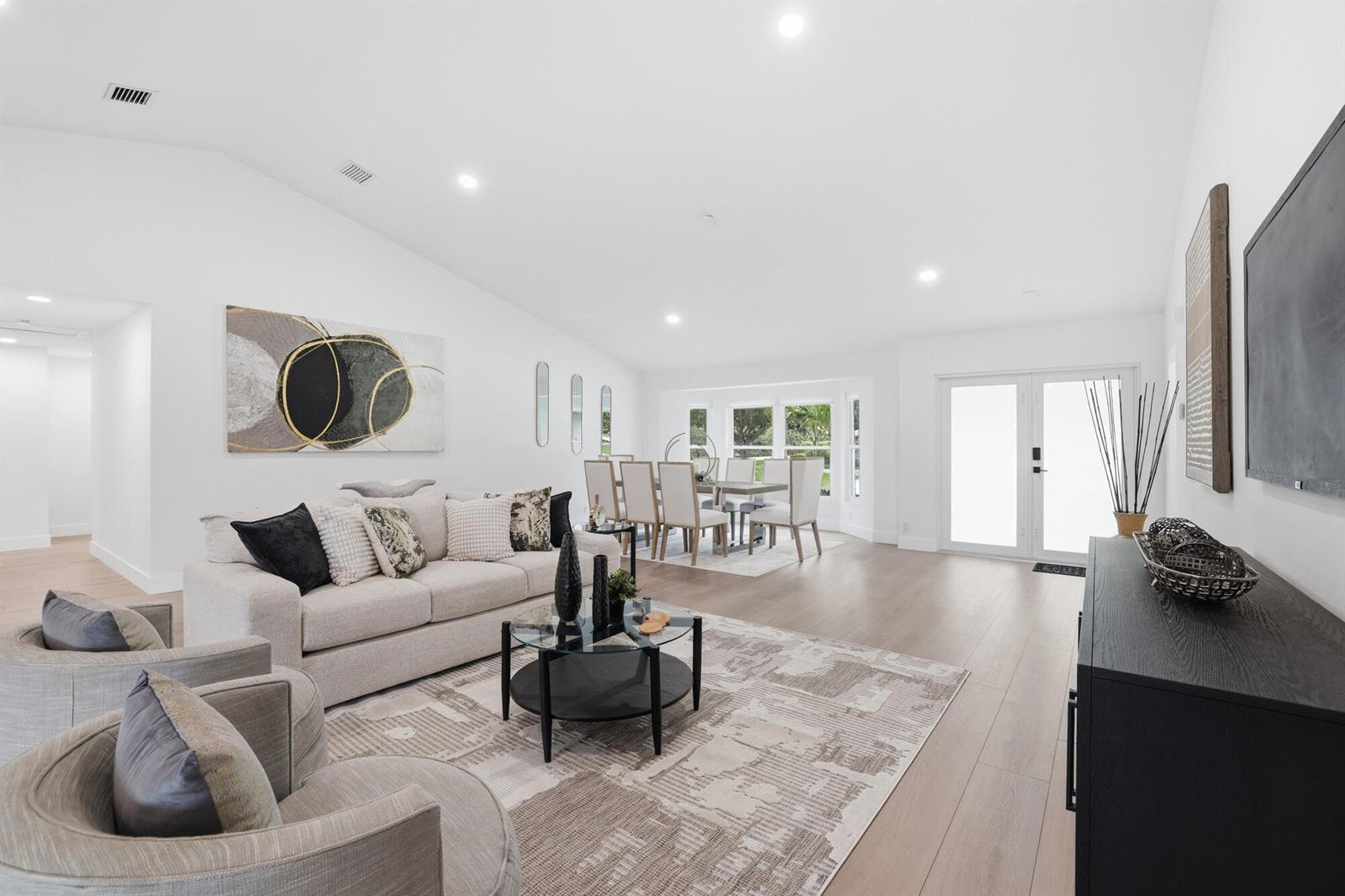 A bright, open-concept living and dining area features light wood flooring and white walls — 7411 Dover Lane, Parkland FL 33067, PARKLAND, FL