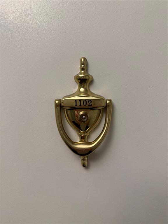 A brass door knocker with the number 1102 is mounted on a plain white door — 345 BAYSHORE BOULEVARD UNIT 1102, TAMPA, FL