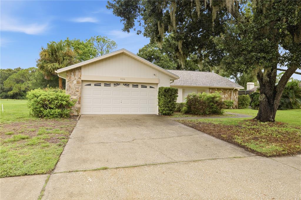 A single-story house with a stone facade, a two-car garage, and a concrete driveway — 3506 FAIRWAY FOREST DRIVE, PALM HARBOR, FL