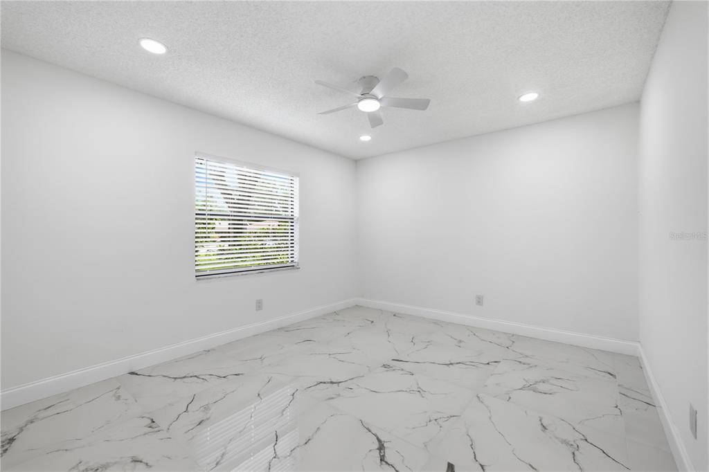 A bedroom with white walls, a ceiling fan, recessed lighting, and white marble-patterned tile flooring — 3506 FAIRWAY FOREST DRIVE, PALM HARBOR, FL