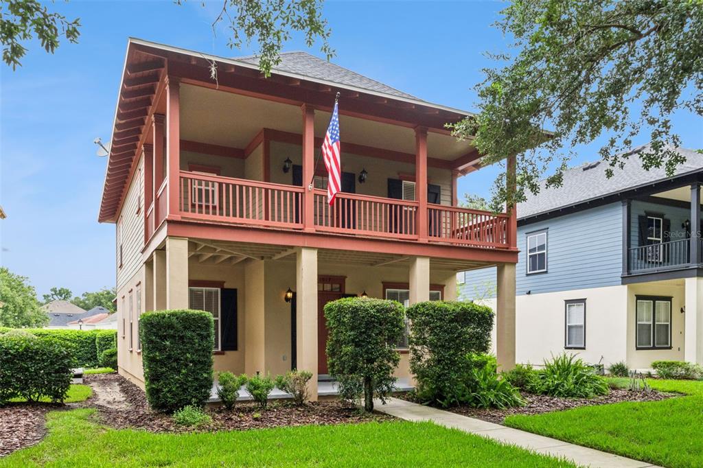 A two-story house with a covered front porch, a balcony, and a red front door — 1017 OLD BLUSH ROAD, KISSIMMEE, FL