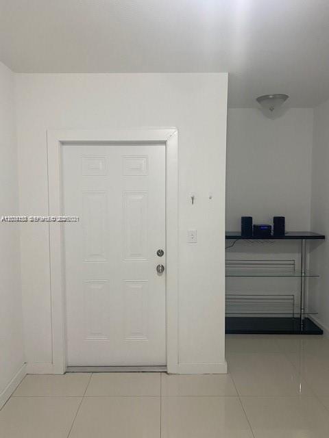 A white front door stands next to a glass and metal shelving unit on tiled floors — 2271/2273 NW 66th St, Miami FL 33147, MIAMI, FL