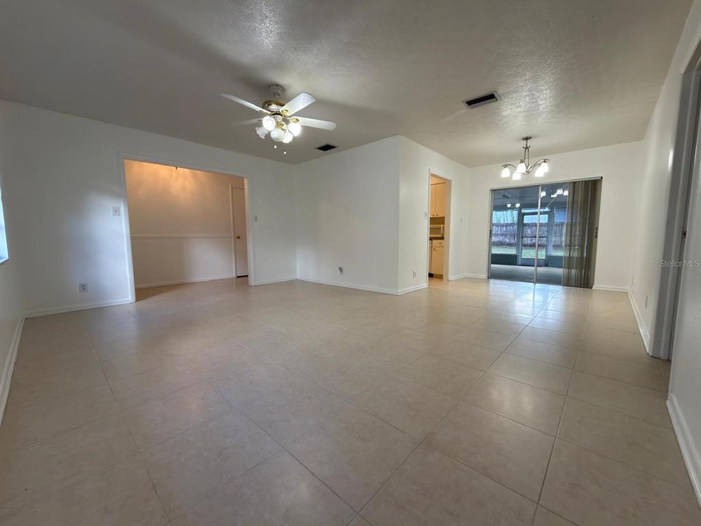 An open-concept living area features light-colored tile flooring, white walls, and a ceiling fan — 2209 BOXWOOD WAY, BRANDON, FL