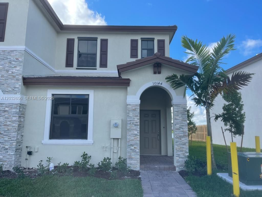 A two-story house exterior features a stone-accented entryway, a gray front door, and shutters — 10144 SW 228th Ter, Miami FL 33190, MIAMI, FL
