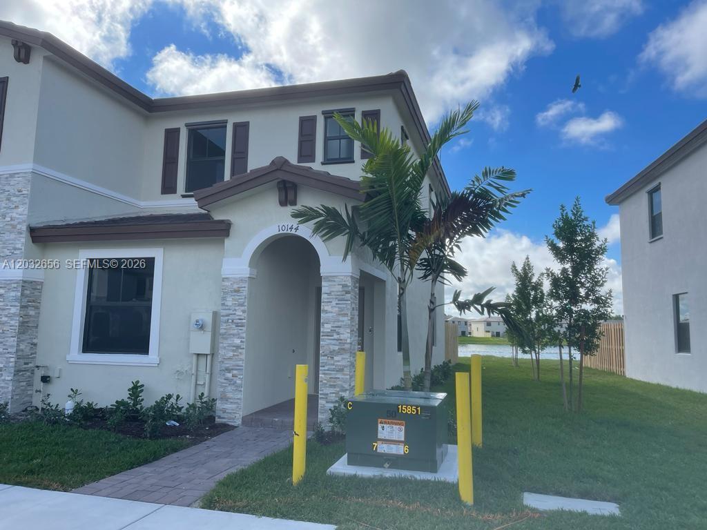 A two-story house exterior features a stone-accented entryway, a palm tree, and a utility box — 10144 SW 228th Ter, Miami FL 33190, MIAMI, FL