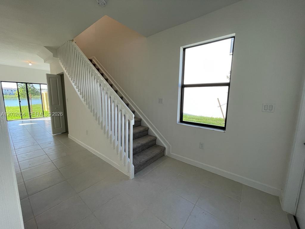 An interior view shows a tiled entryway with a carpeted staircase and a large window — 10144 SW 228th Ter, Miami FL 33190, MIAMI, FL