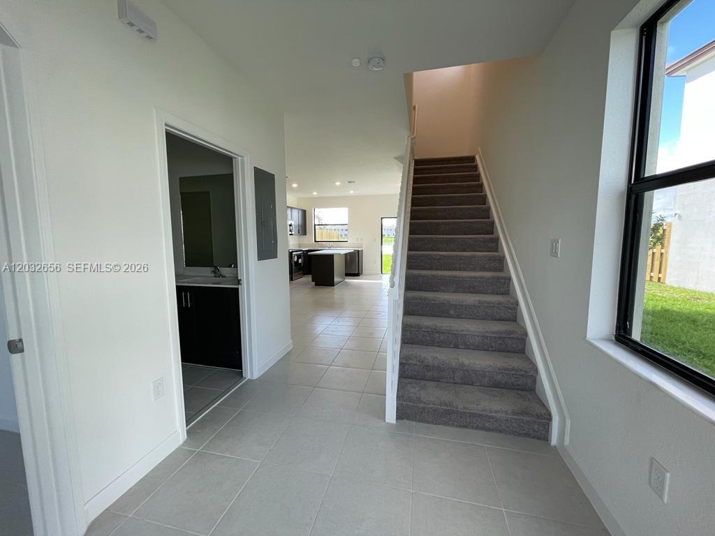 An interior view shows a tiled entryway, a carpeted staircase, and a kitchen in back — 10144 SW 228th Ter, Miami FL 33190, MIAMI, FL