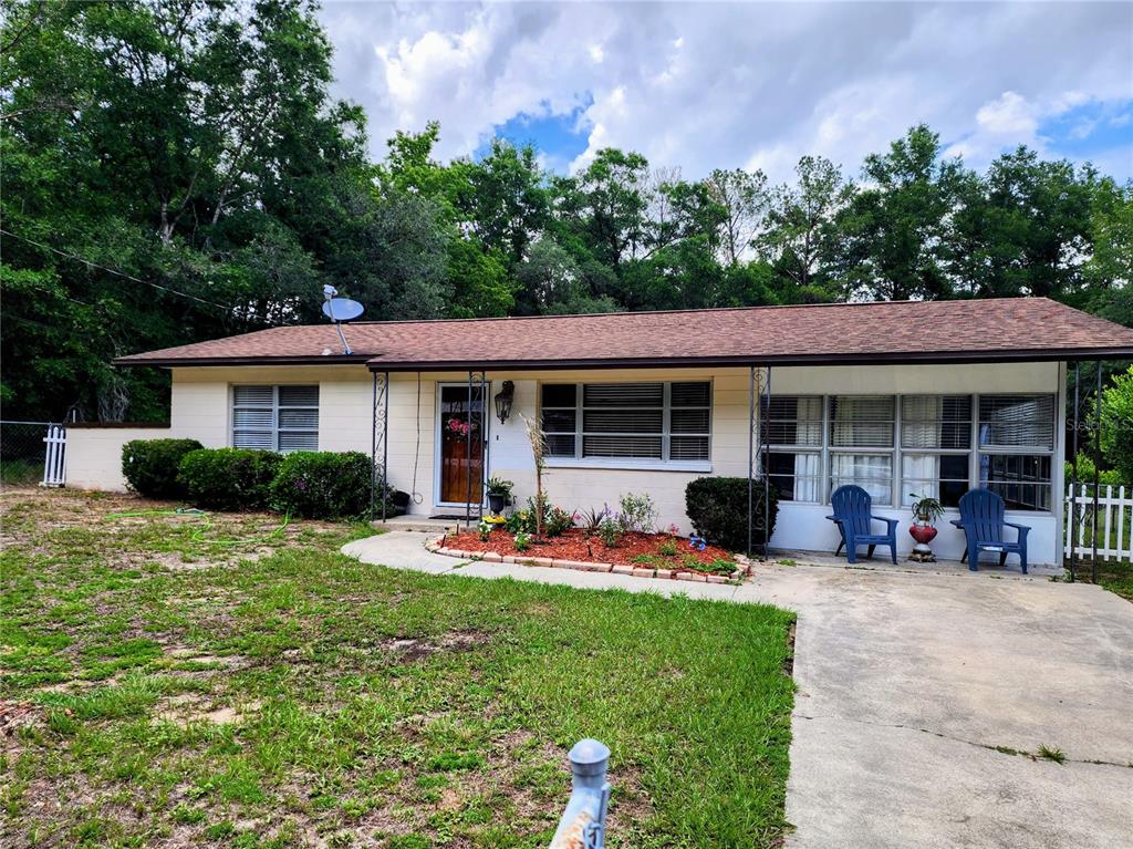 A single-story house with a concrete driveway, a front porch, and a landscaped garden bed — 19729 SW LARK DRIVE, DUNNELLON, FL