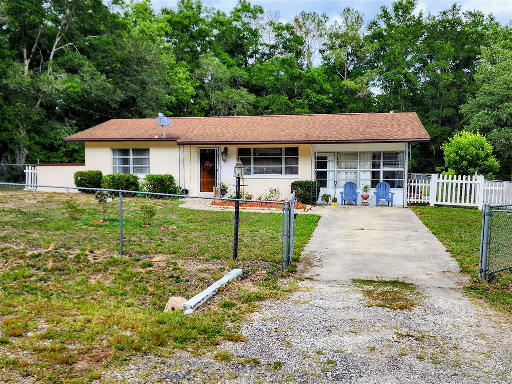 A single-story house with a brown roof, beige exterior, and a concrete driveway — 19729 SW LARK DRIVE, DUNNELLON, FL