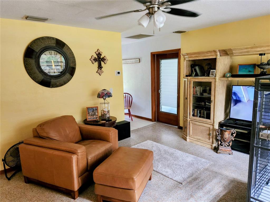 A living room features a large brown sectional sofa, a patterned area rug, and yellow walls — 19729 SW LARK DRIVE, DUNNELLON, FL