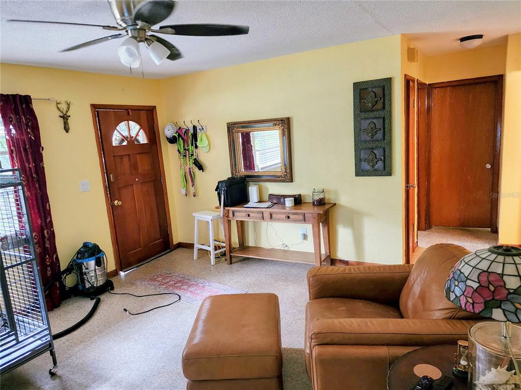 A living room features a large wooden entertainment center with glass-front cabinets and a television — 19729 SW LARK DRIVE, DUNNELLON, FL