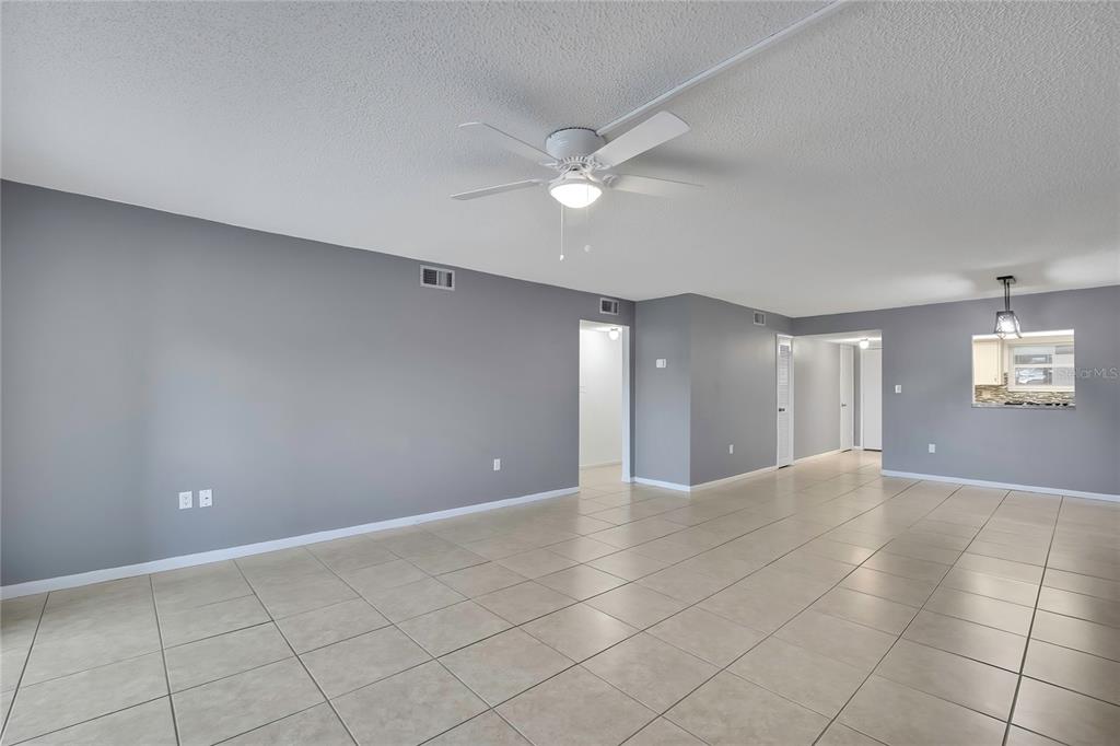 An empty room features gray walls, a white ceiling fan, and light-colored tiled flooring — 4452 GARNET DRIVE UNIT 203, NEW PORT RICHEY, FL