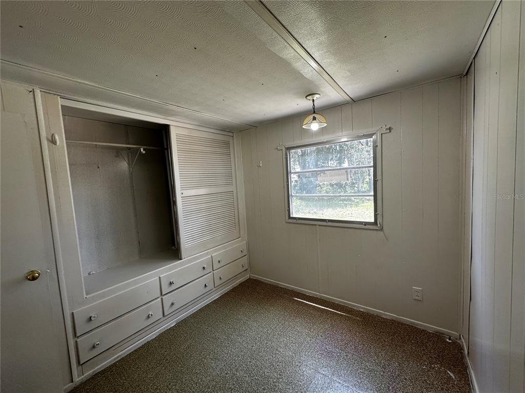 A bedroom features wood-paneled walls, a built-in closet with drawers, and a single window — 817 PARKS STREET, WILDWOOD, FL