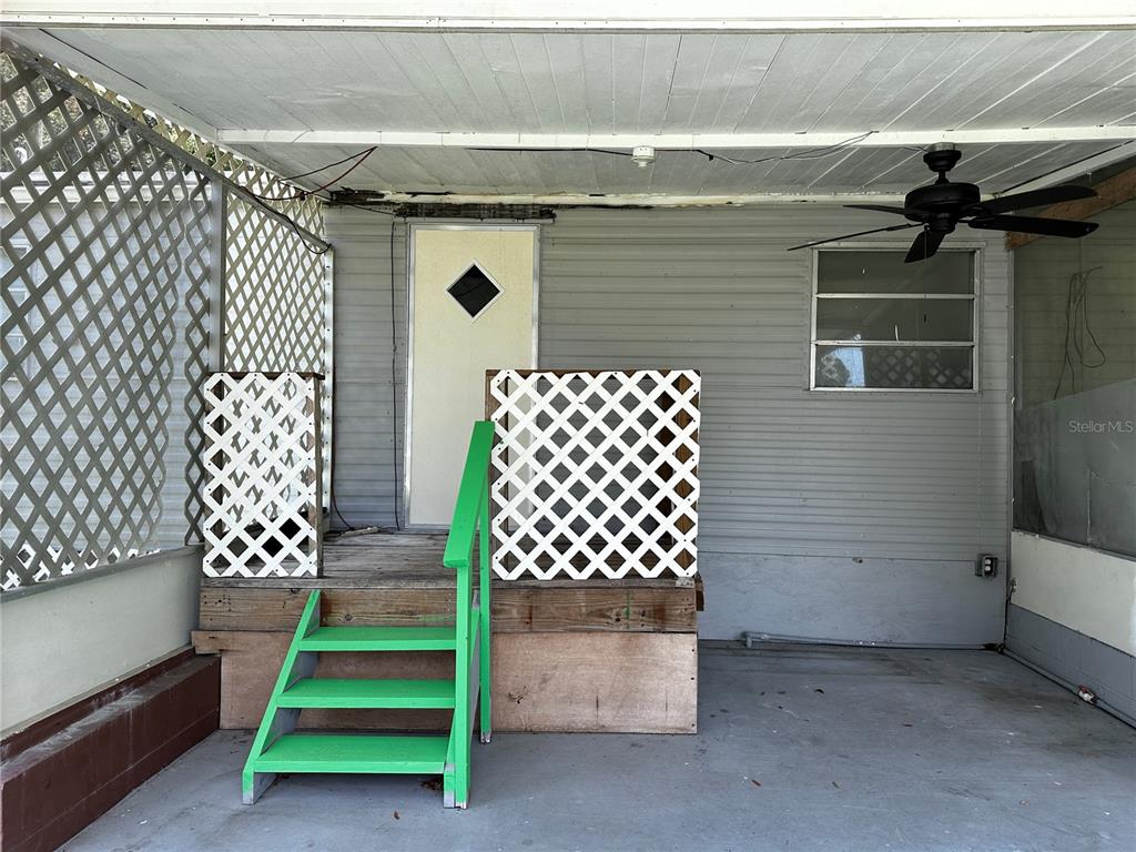 A covered patio features a wooden deck with green steps and white lattice privacy screens — 817 PARKS STREET, WILDWOOD, FL