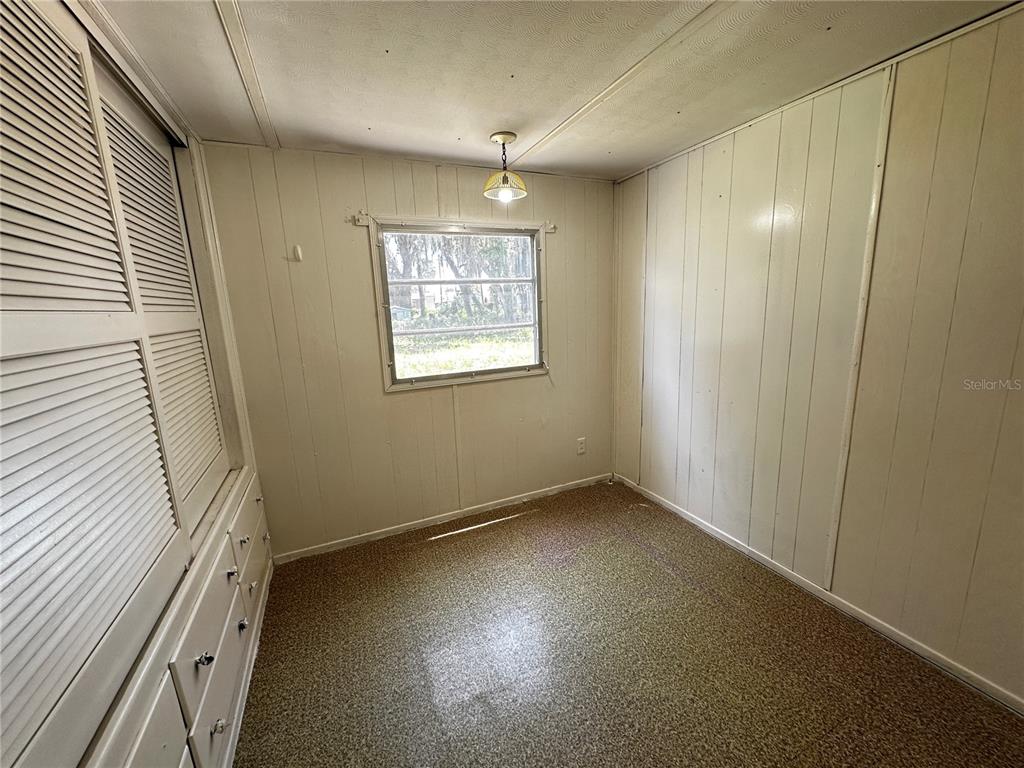 A bedroom with white paneled walls, a built-in dresser, and a single window — 817 PARKS STREET, WILDWOOD, FL