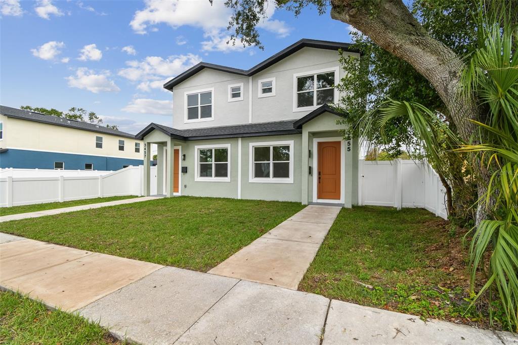A two-story duplex with light green stucco siding, dark trim, and two orange front doors — 3455 17TH AVENUE S, ST PETERSBURG, FL