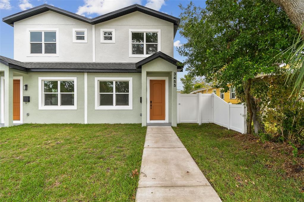 A two-story duplex with light green siding, a concrete walkway, and a brown front door — 3455 17TH AVENUE S, ST PETERSBURG, FL