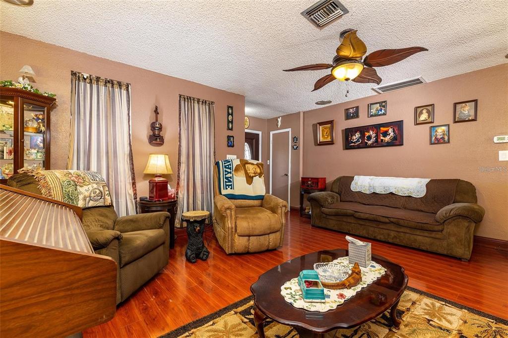 A living room features brown walls, wood flooring, a ceiling fan, and brown furniture — 12095 102ND AVENUE, SEMINOLE, FL