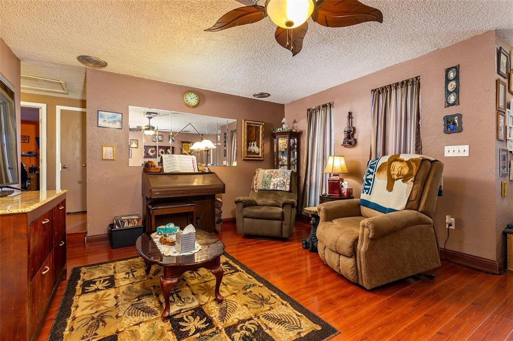 A living room features hardwood floors, a ceiling fan, a recliner, and an upright piano — 12095 102ND AVENUE, SEMINOLE, FL