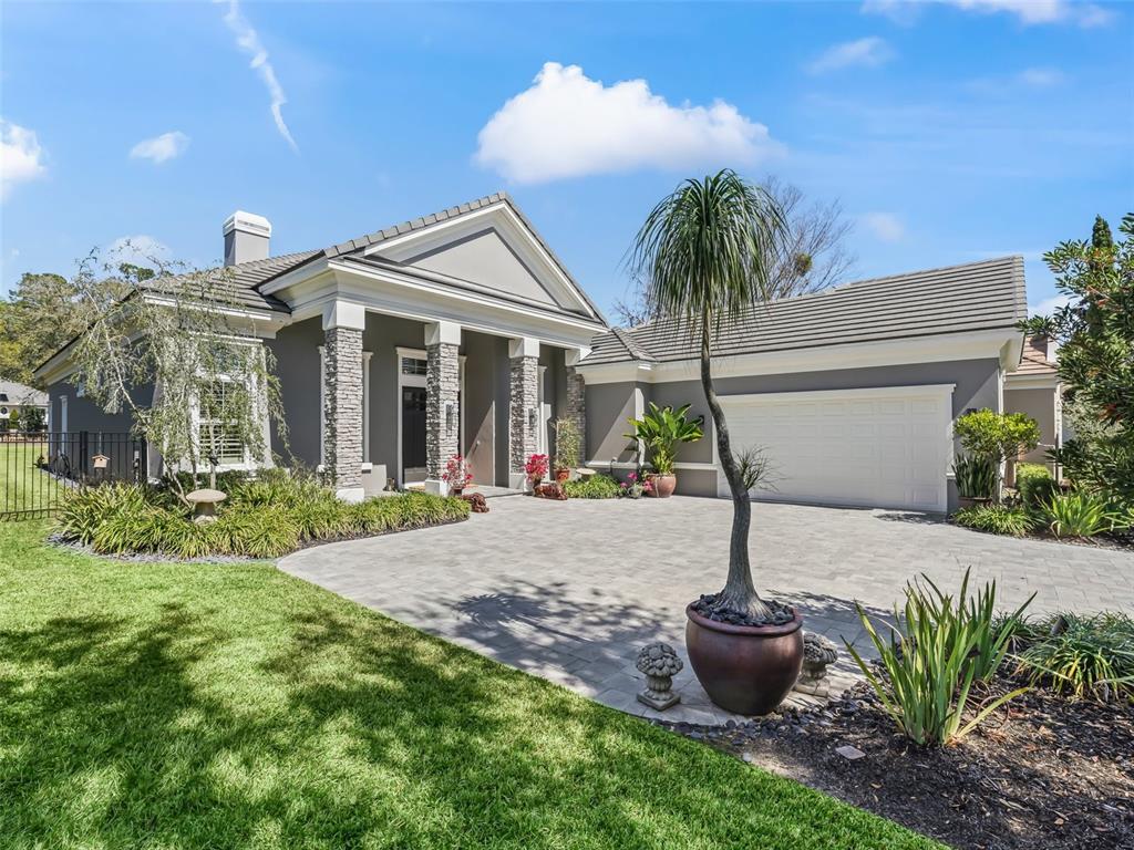 A gray house with a stone-columned entrance, a paved driveway, and a potted palm tree — 8033 NW 28TH STREET, OCALA, FL