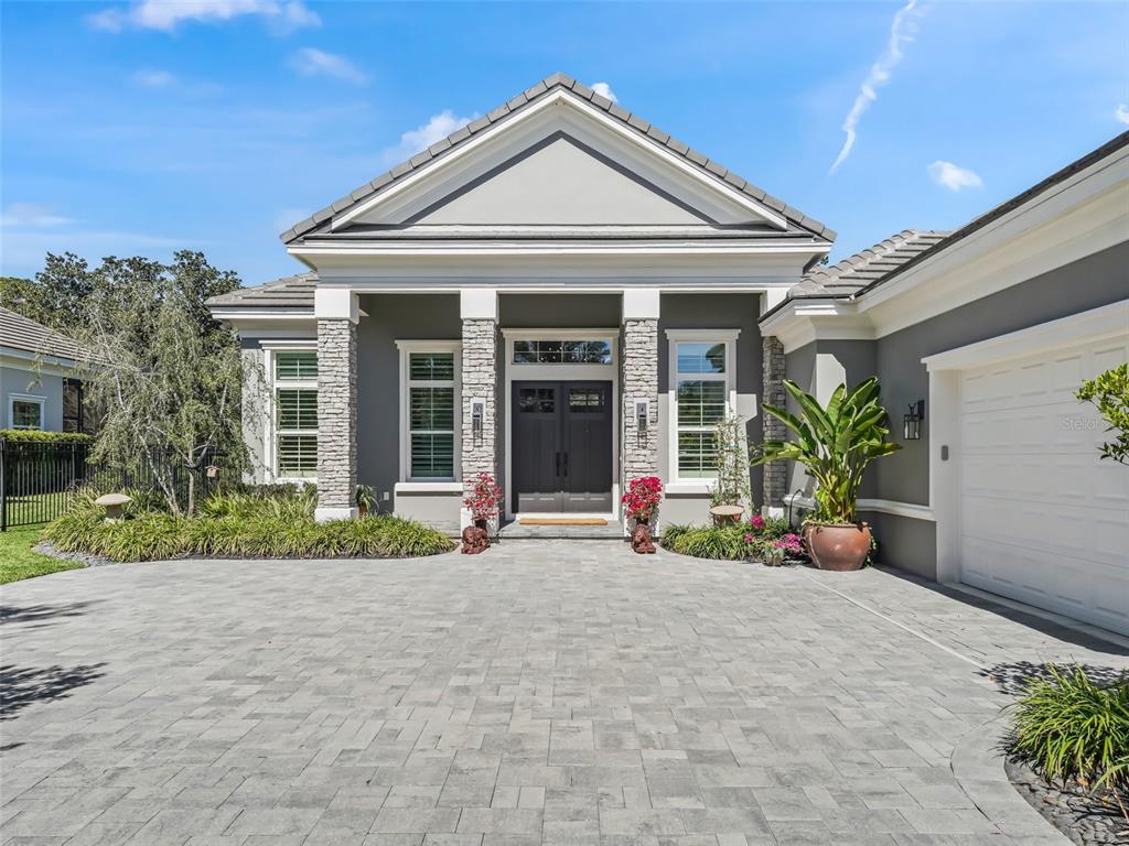 The exterior of a gray house features a stone-accented entryway and a paved driveway — 8033 NW 28TH STREET, OCALA, FL