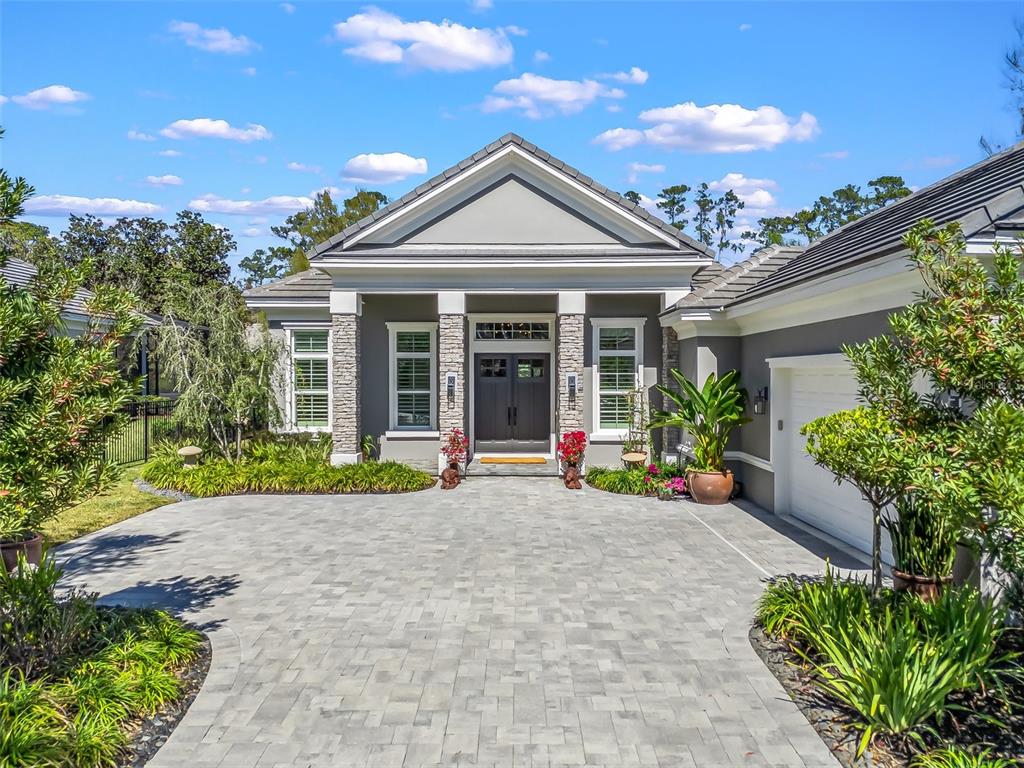 A gray house with a stone-accented entryway and a paved driveway under a blue sky — 8033 NW 28TH STREET, OCALA, FL