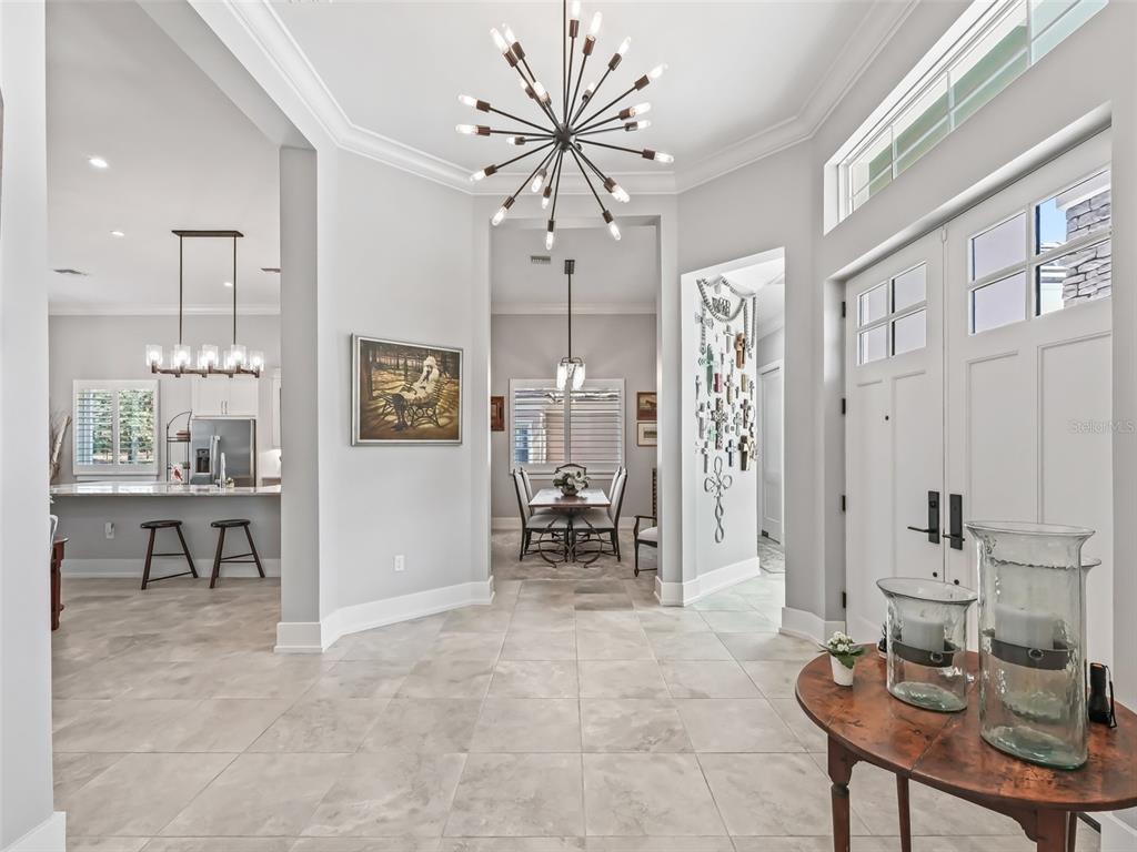 A bright foyer with tile flooring, a modern chandelier, and views into the dining area — 8033 NW 28TH STREET, OCALA, FL