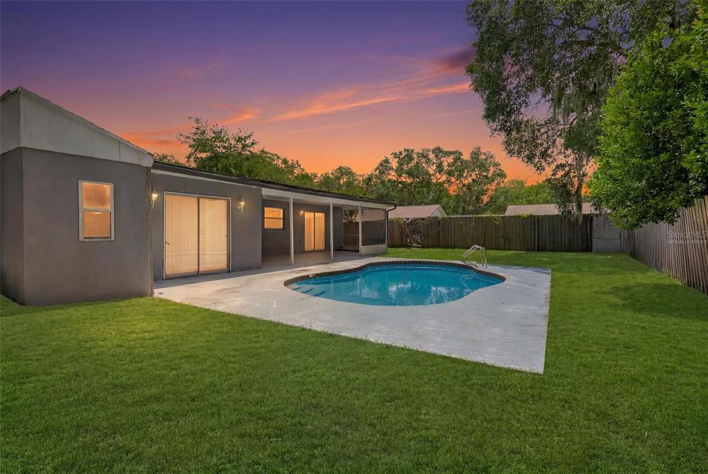 A backyard features a swimming pool, a concrete patio, and a house with sliding doors — 3874 TAM DRIVE, ORLANDO, FL