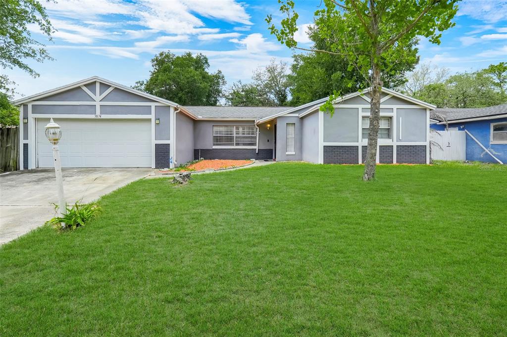 A single-story house with a gray exterior, white garage door, and a large front lawn — 3874 TAM DRIVE, ORLANDO, FL