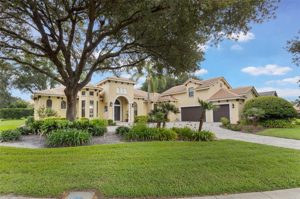A single-story stucco house with a tile roof, a large tree, and a paved driveway — 25514 HIGH HAMPTON CIRCLE, SORRENTO, FL