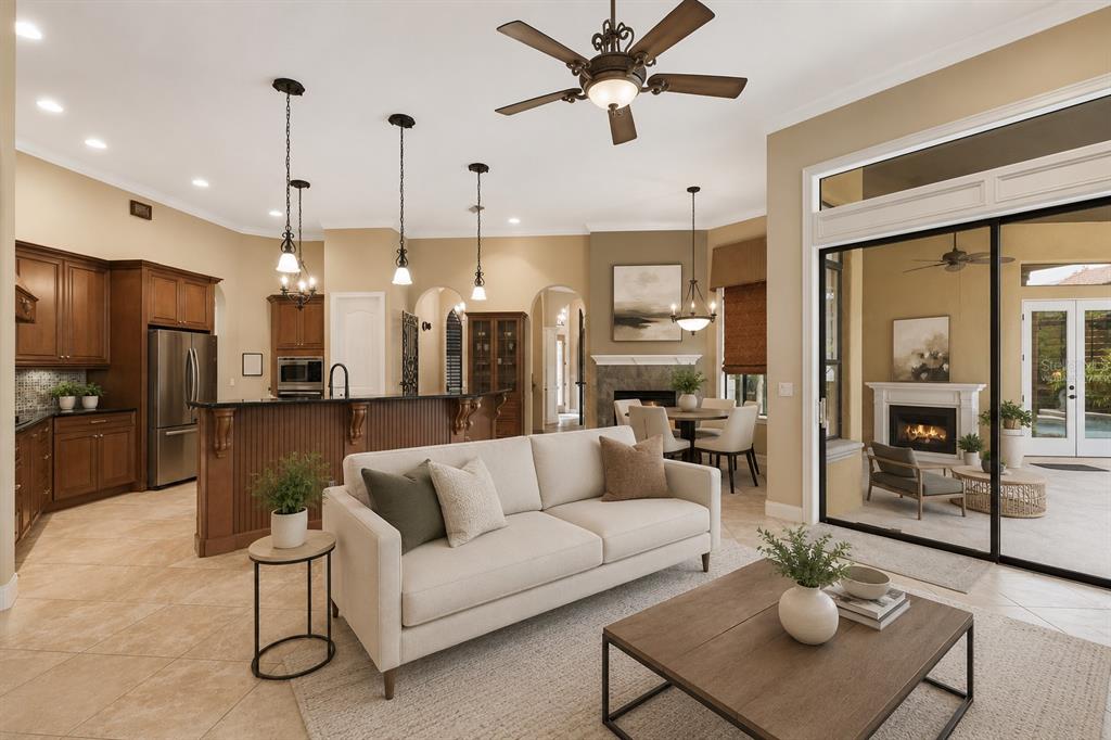 An open-concept living room and kitchen with tile floors, wooden cabinetry, and a covered patio — 25514 HIGH HAMPTON CIRCLE, SORRENTO, FL