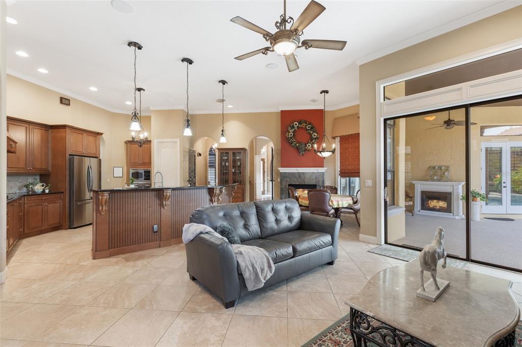 A living room and kitchen area features tile floors, a fireplace, and a sliding glass door — 25514 HIGH HAMPTON CIRCLE, SORRENTO, FL